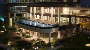 Un hotel moderno con piscina en la azotea, varias plantas y zonas de estar al aire libre.