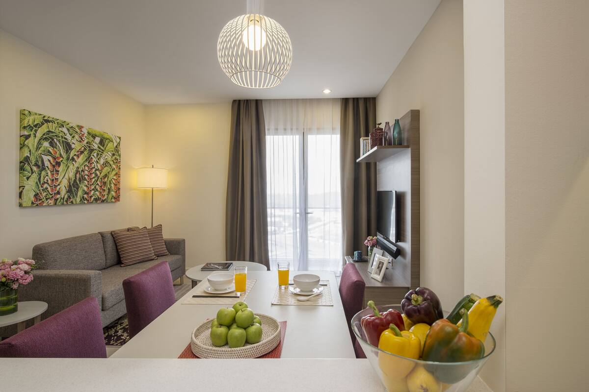 Ein modernes Wohnzimmer mit Sofa, Esstisch und Obstschale.
