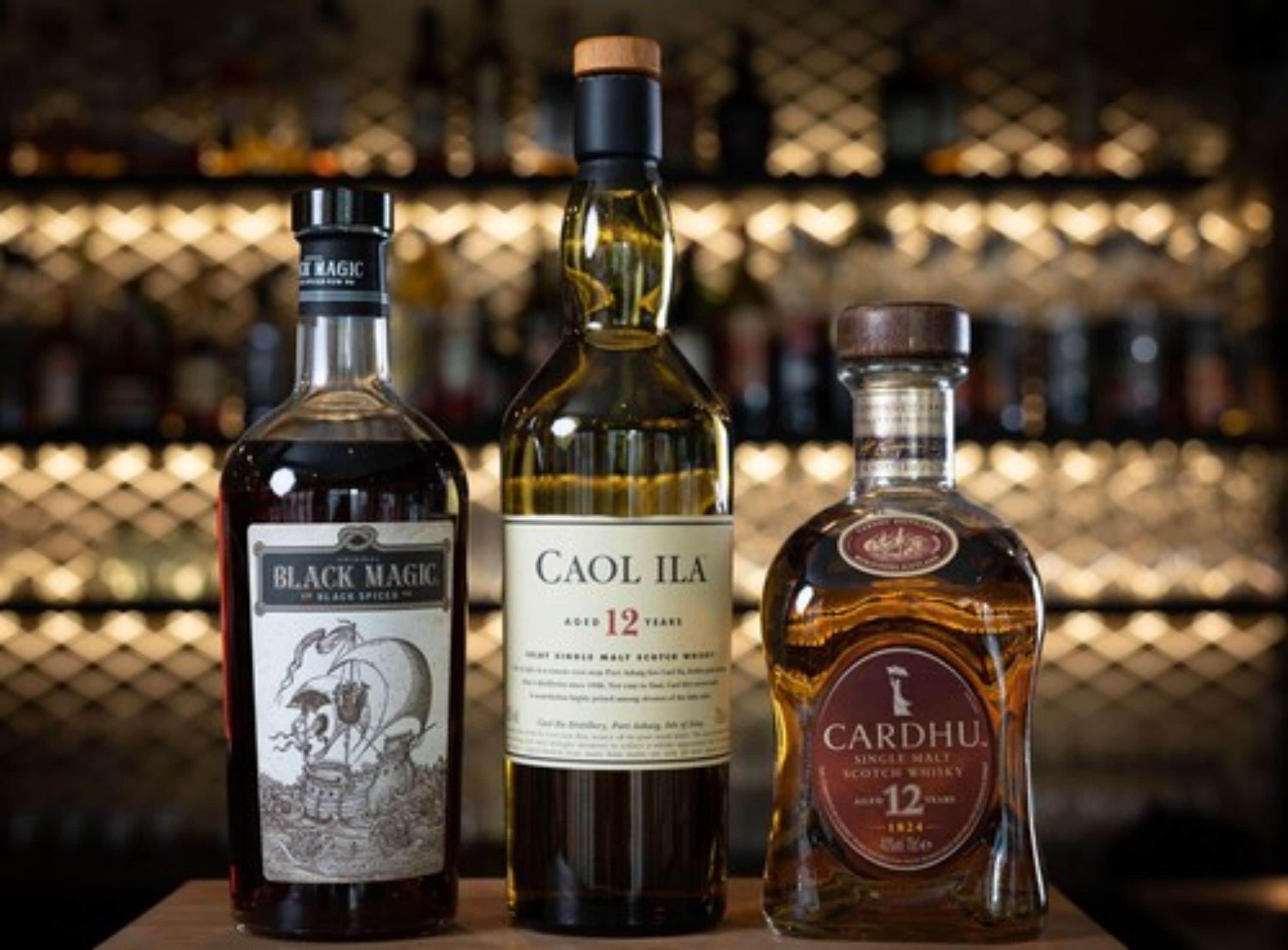Trois bouteilles de whisky sur une table.