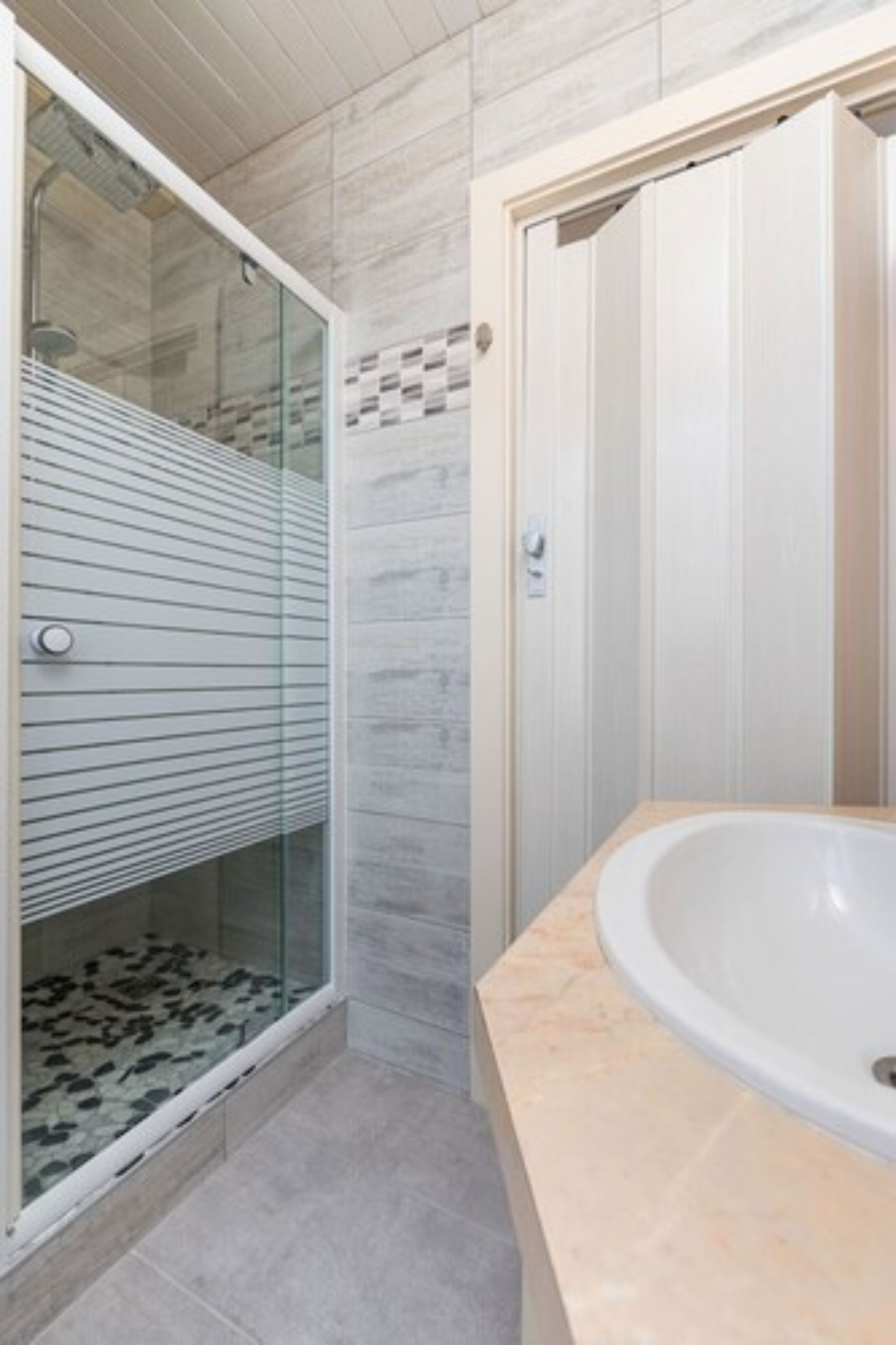 Ein modernes Badezimmer mit einer Duschkabine aus Glas, einer weißen Badewanne und einem gefliesten Boden.