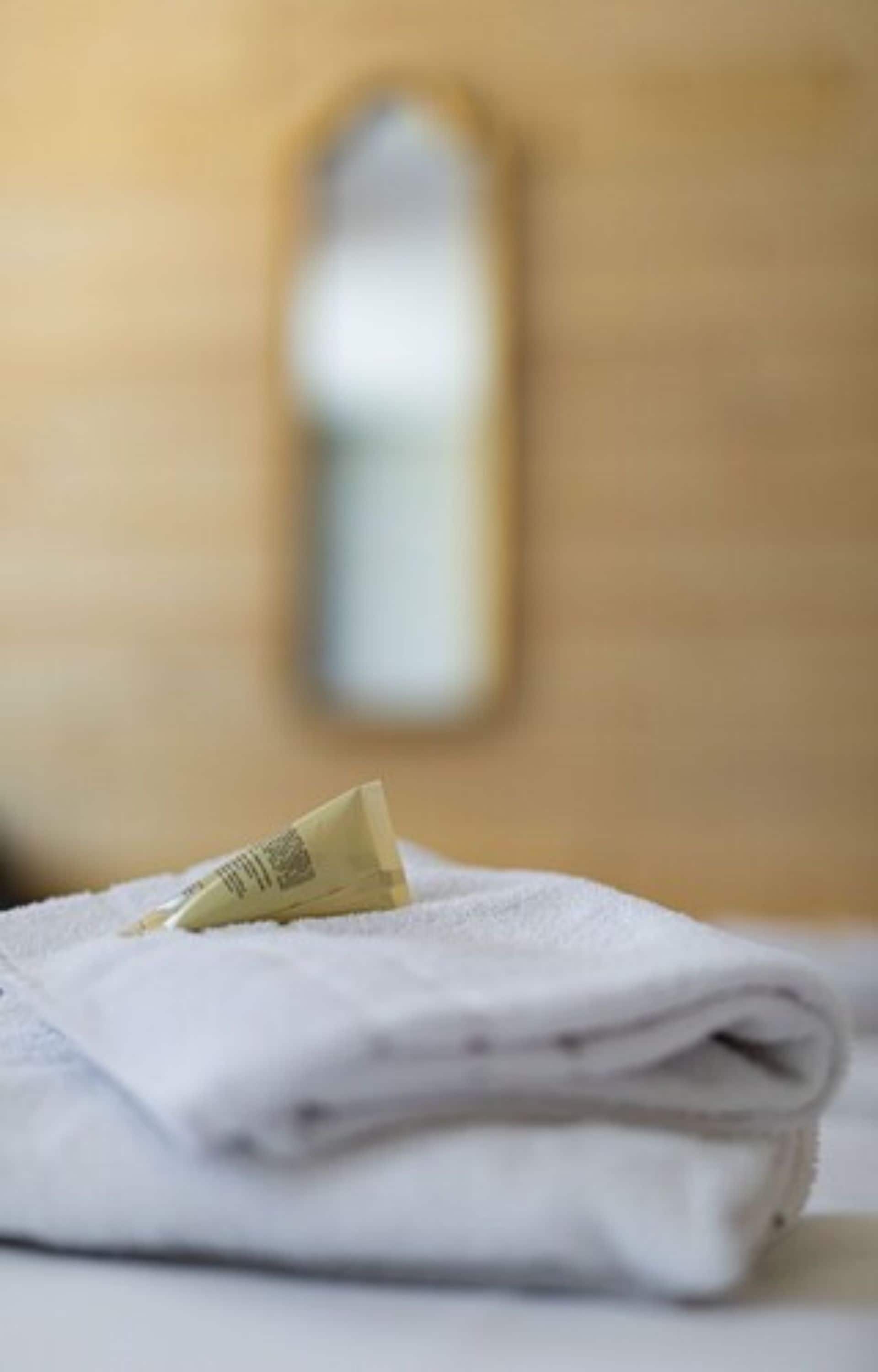 A folded white towel on a surface with a blurred background.