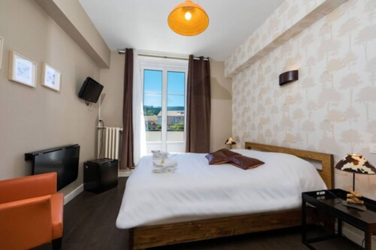 Habitación de hotel con cama, televisión, escritorio y vistas al exterior.