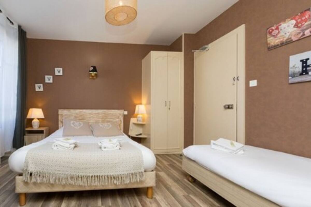 Un dormitorio con cama, una mesita de noche con lámpara, un armario y otra mesita de noche con lámpara.