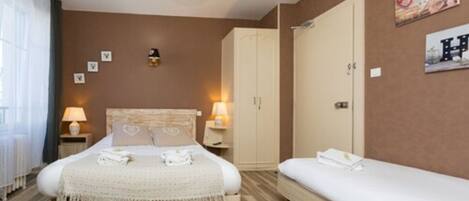 A bedroom with a bed, a bedside table with a lamp, a wardrobe, and a small bedside table with a lamp.