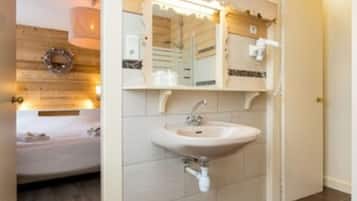 Une salle de bain avec un plafond en bois, un lavabo blanc et un miroir au-dessus.