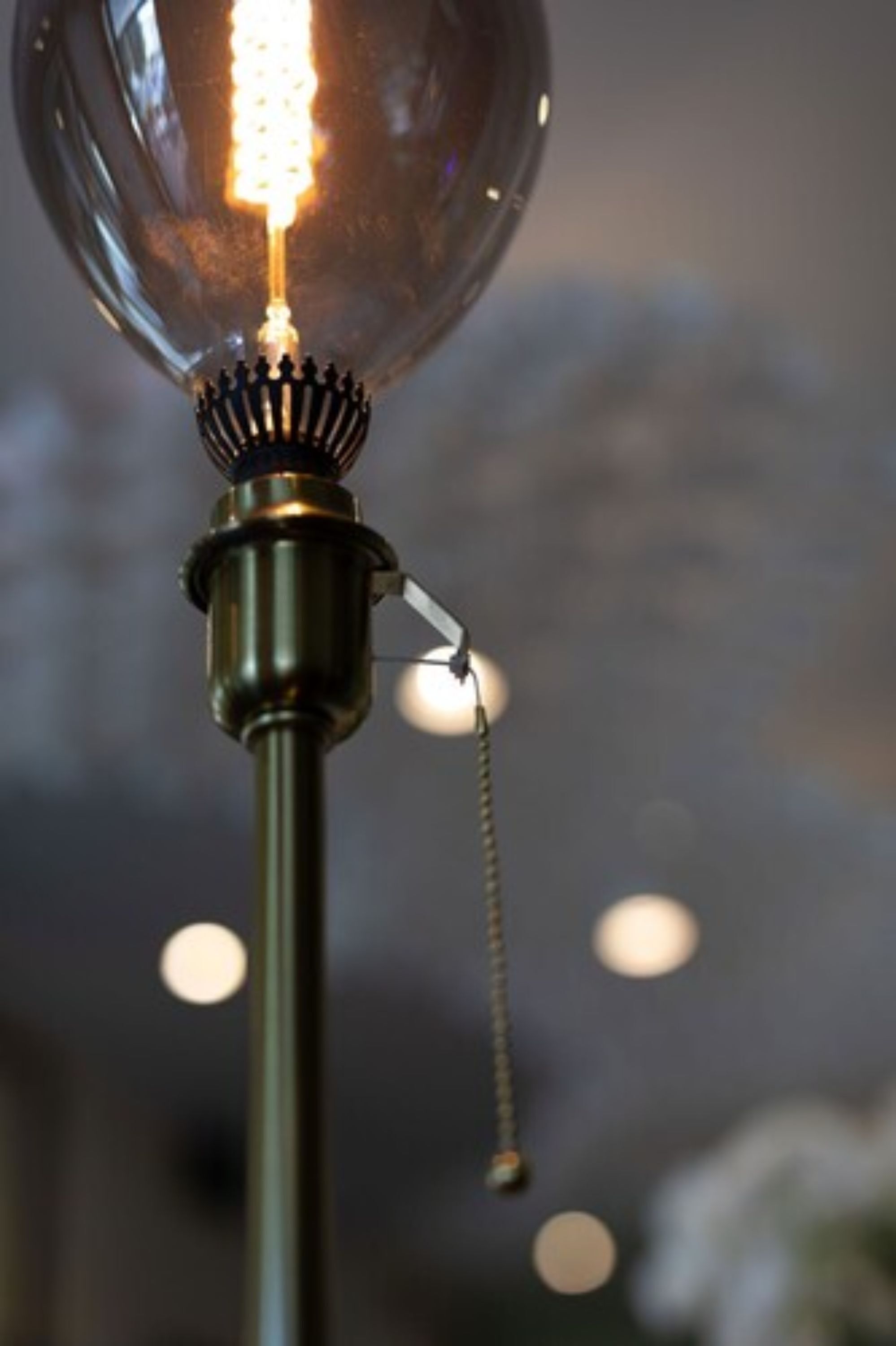 A close-up of a clear glass bulb light fixture with a visible filament and a metal base.