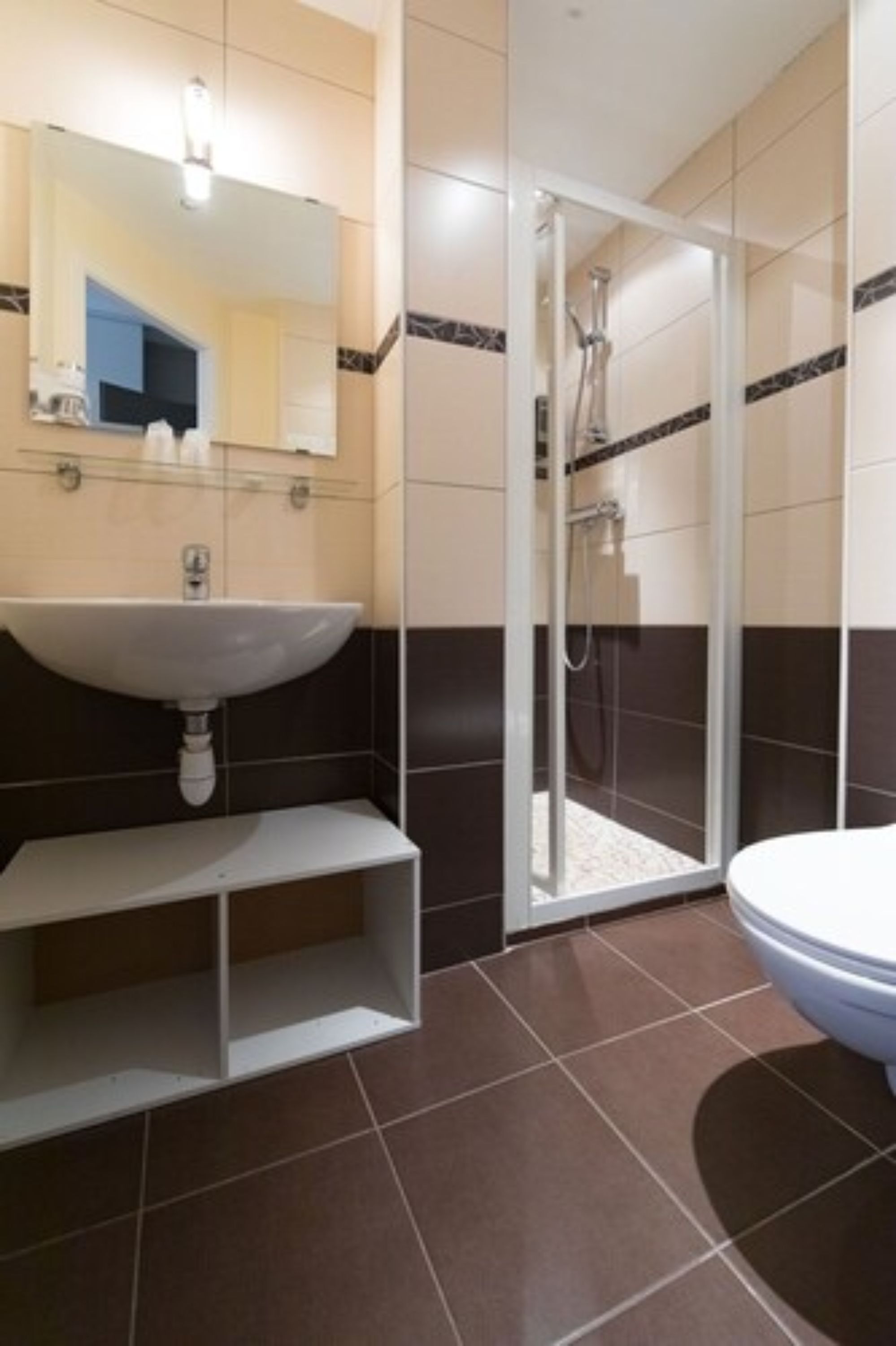A bathroom with a sink, mirror, shower, and toilet.