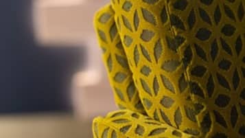 A close-up of a yellow patterned fabric, likely part of a piece of furniture.