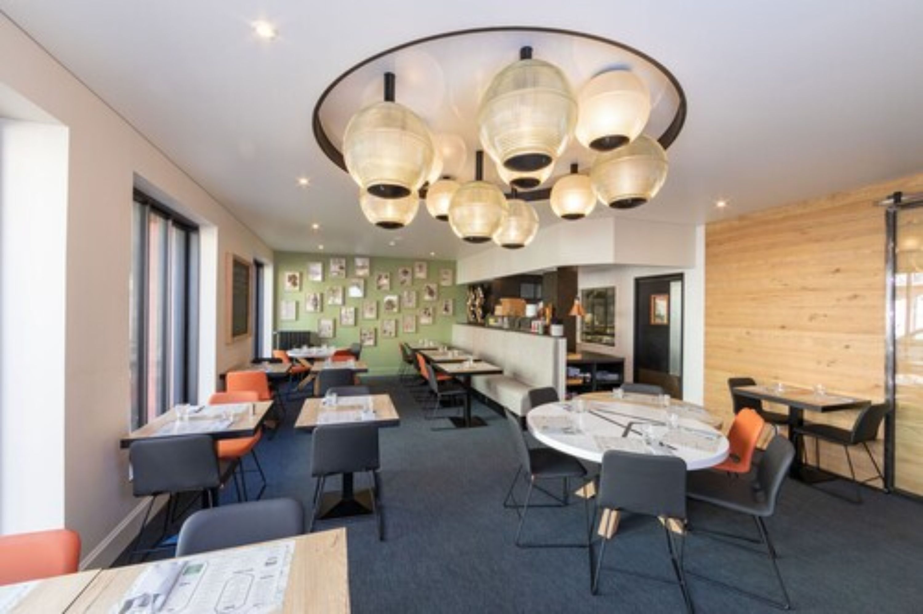Een moderne eetruimte met ronde tafels en stoelen, een bar en een wand met ingekaderde foto's.