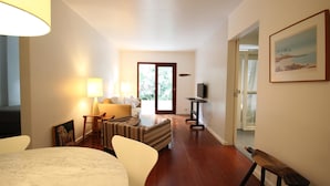 A spacious living room with a sofa, a dining table, and a TV. There is a door leading to a balcony. - Gomide SP 21 (São Paulo)