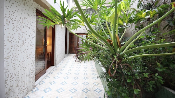 A narrow corridor with patterned tile flooring, a wooden door, and a seating area with chairs. - Gomide SP 21 (São Paulo)