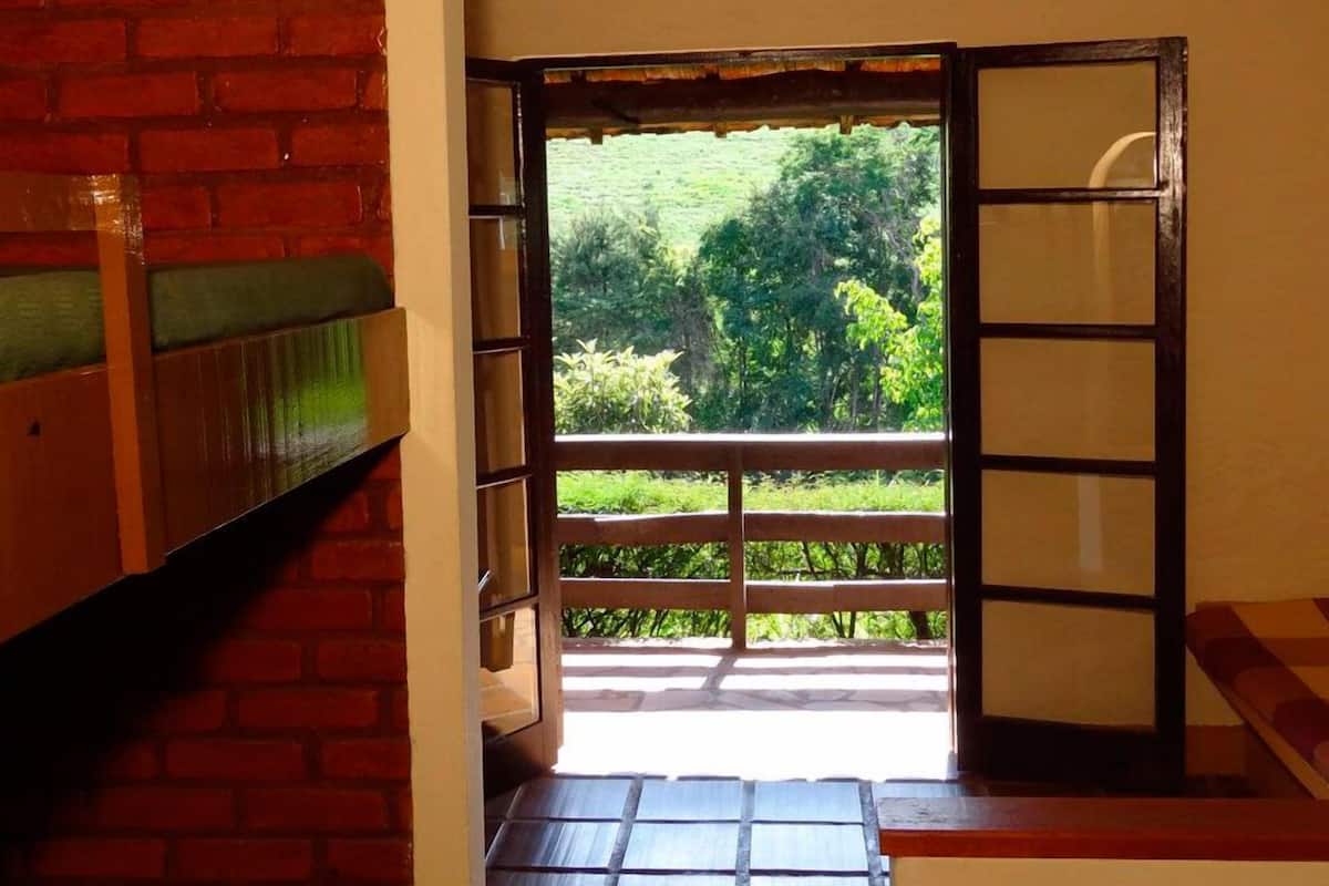 A room with a view of a green landscape through a wooden door.