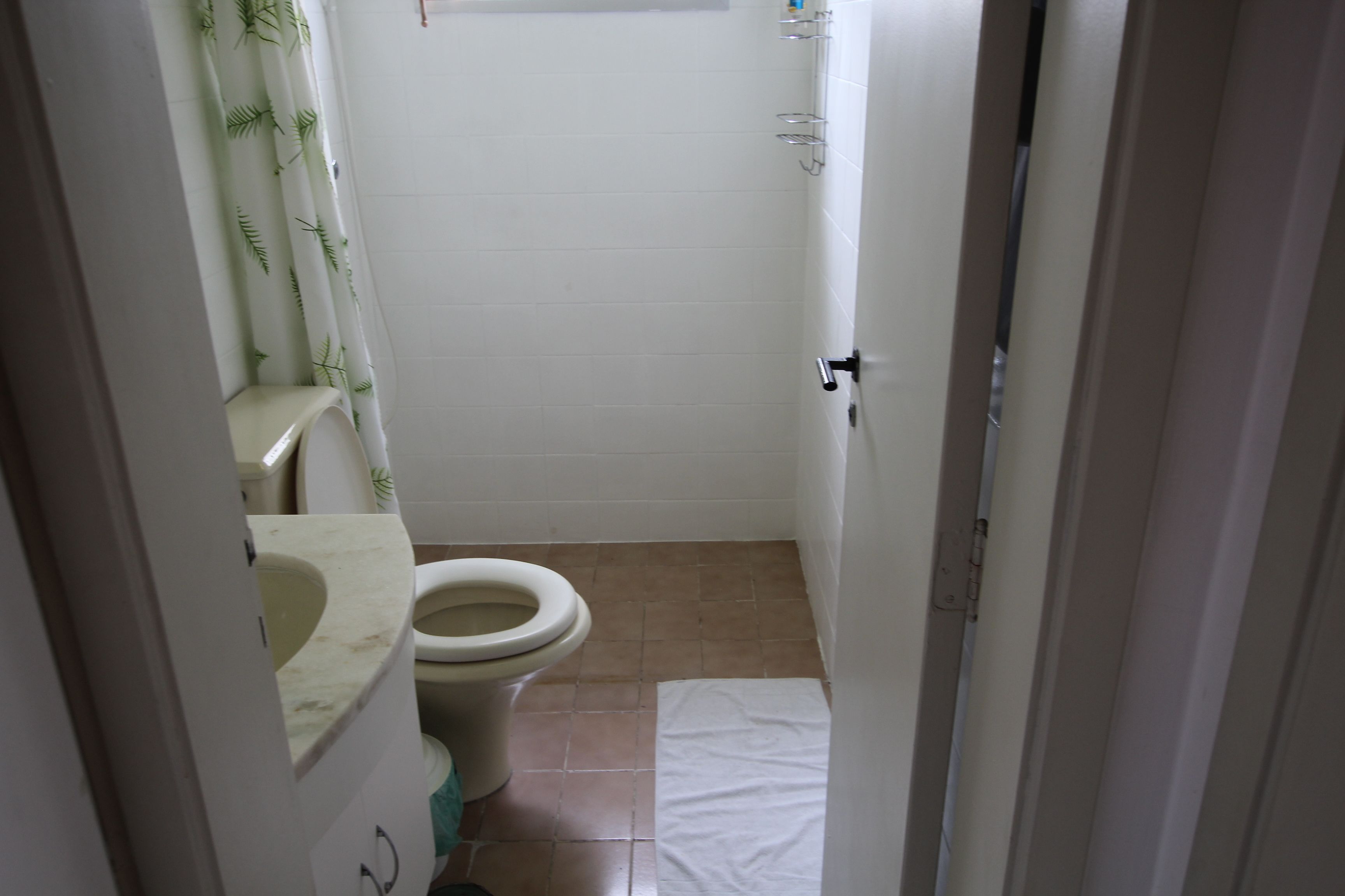 A small bathroom with a toilet, a sink, and a shower area.