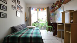 Een slaapkamer met een bed, een bureau, een stoel en een kaart aan de muur.