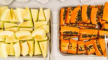 Dos bandejas con frutas cortadas: una con melón y la otra con papaya, sobre una mesa blanca.