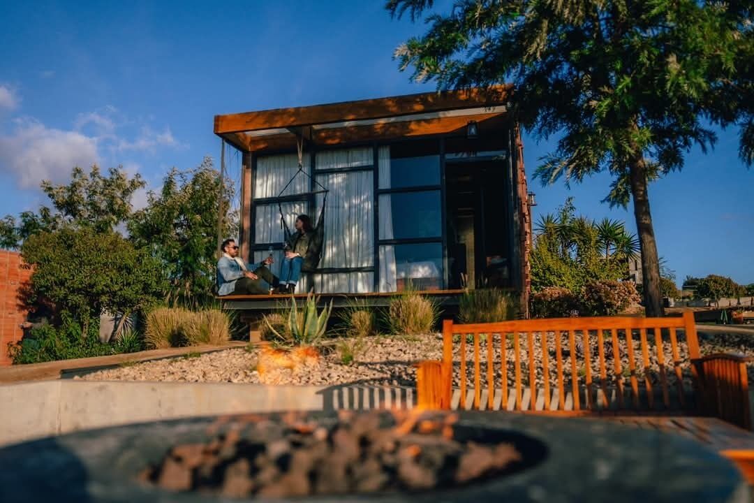 Un edificio moderno con grandes ventanales, una terraza de madera y un área con chimenea.