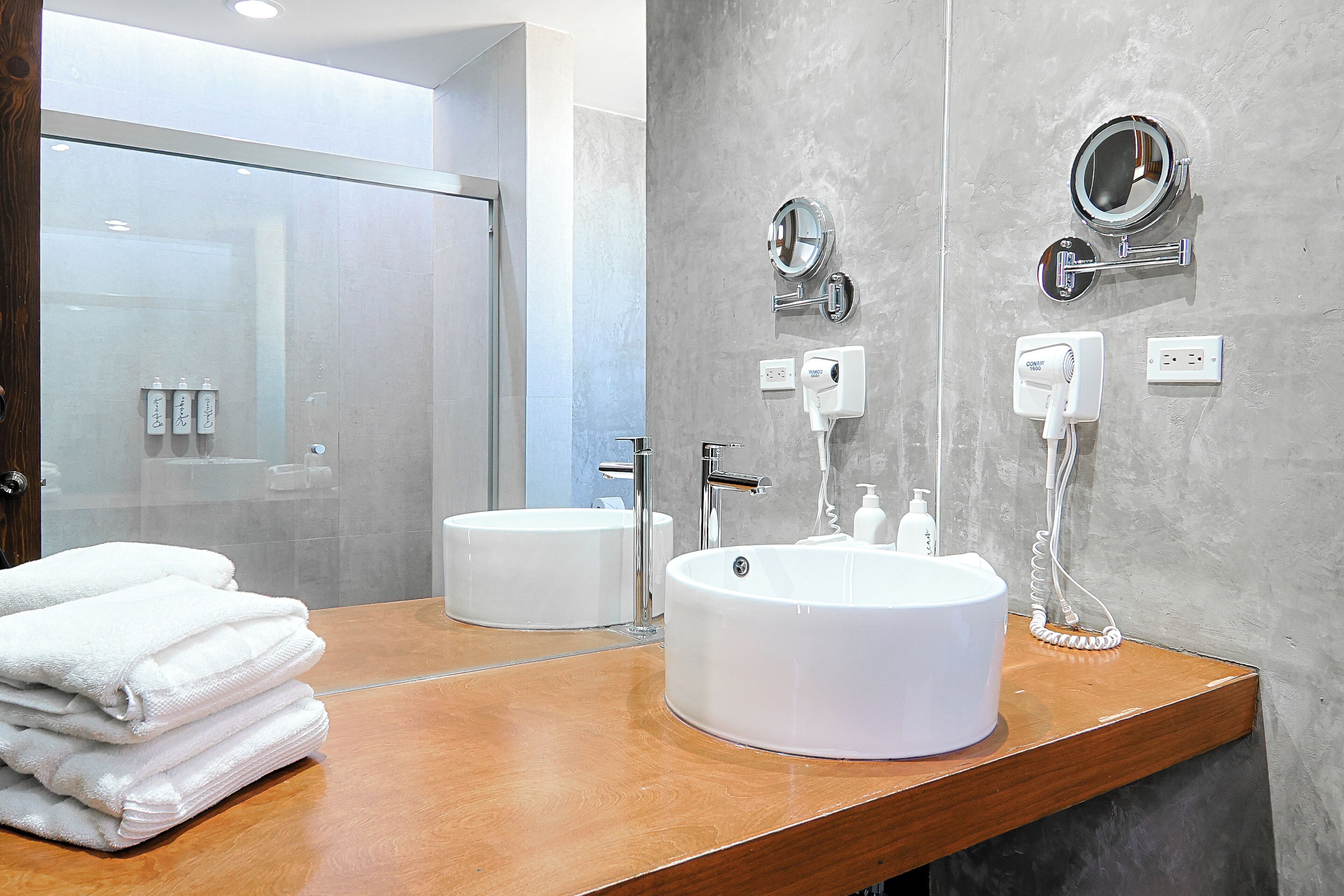 A modern bathroom with two sinks, a large mirror, and a glass shower enclosure.