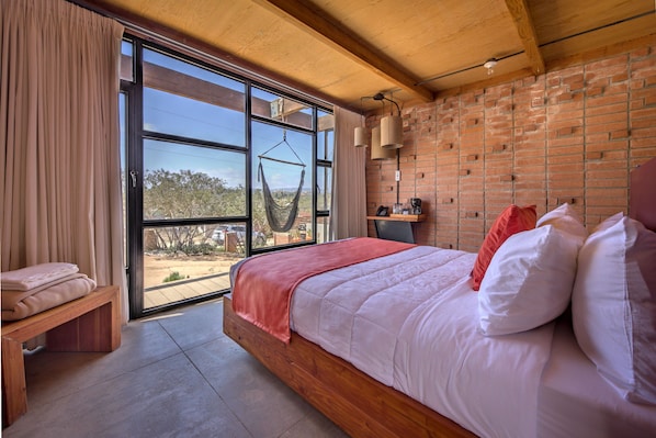 A bedroom with a large bed, a hammock, a bench, and a view of the outdoors. - Maglen Resort (Valle de Guadalupe)
