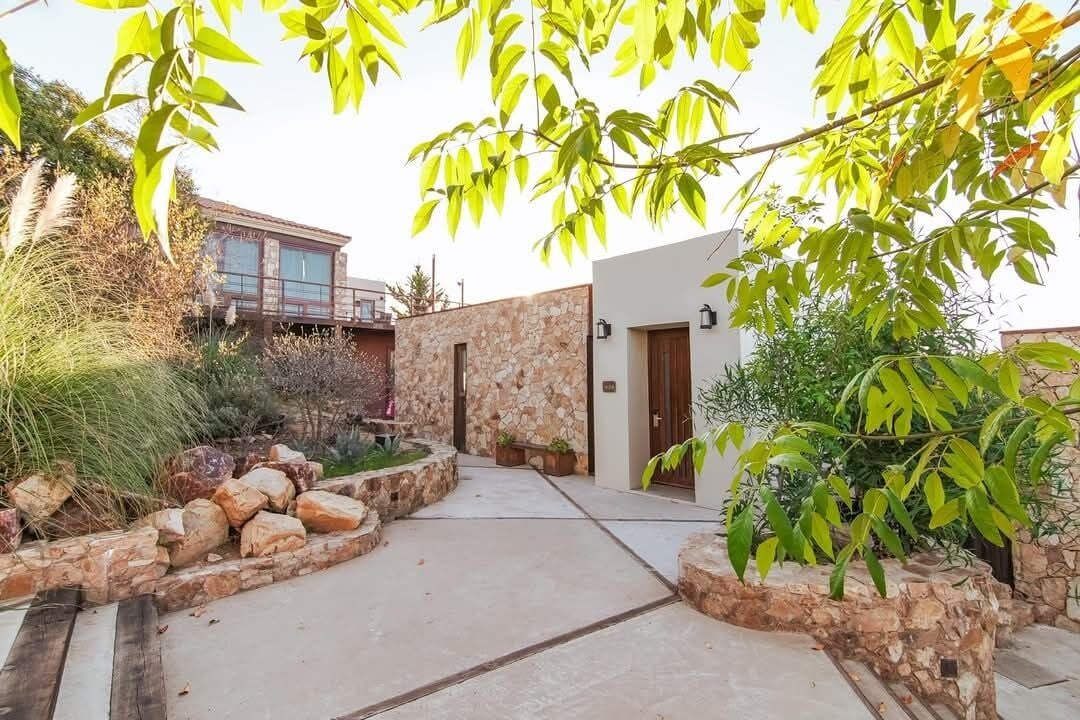 Une cour bordée de murs en pierre, une terrasse en bois et un bâtiment moderne doté d’une façade en pierre.