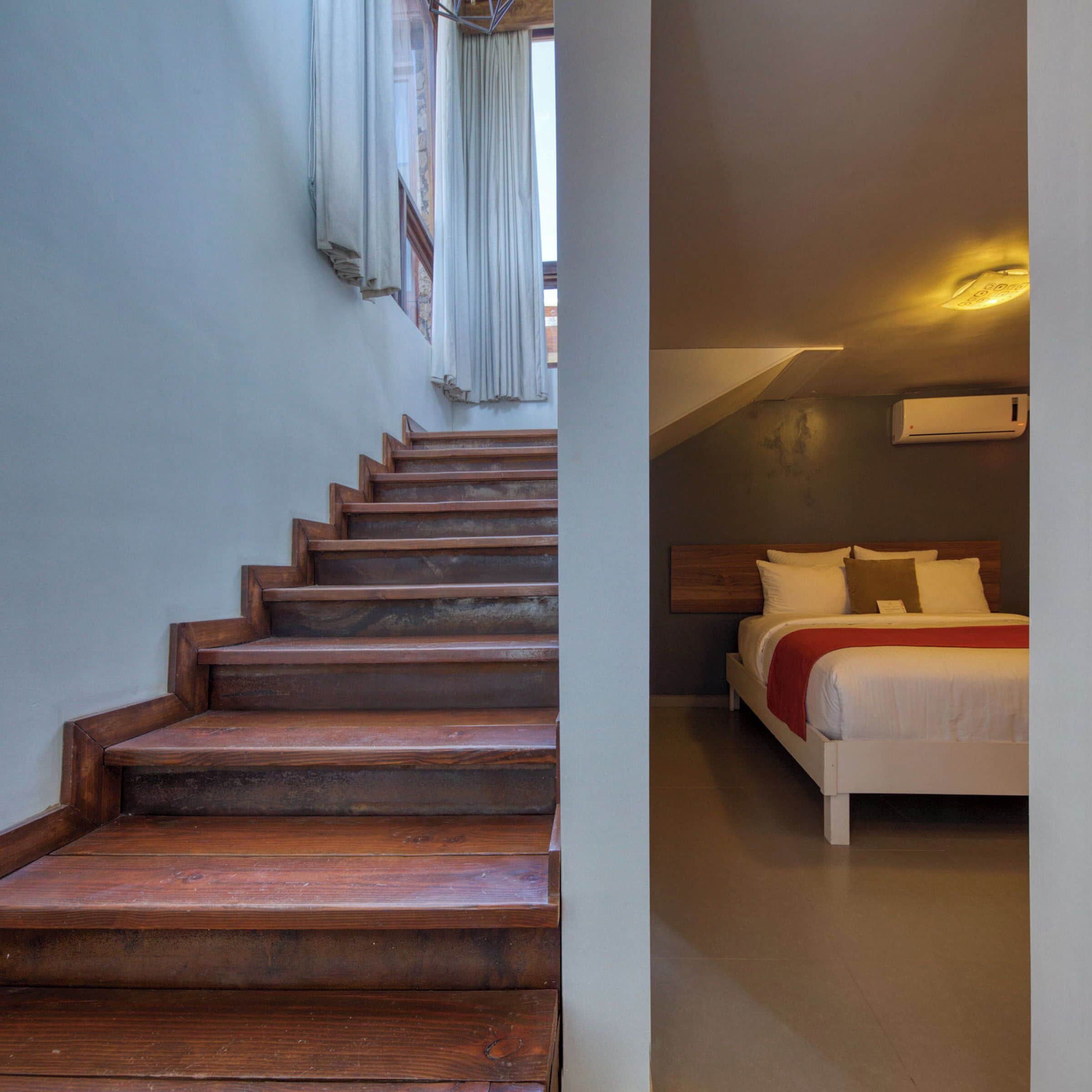 A staircase leading to a bedroom with a bed, a headboard, and a wall-mounted air conditioner.