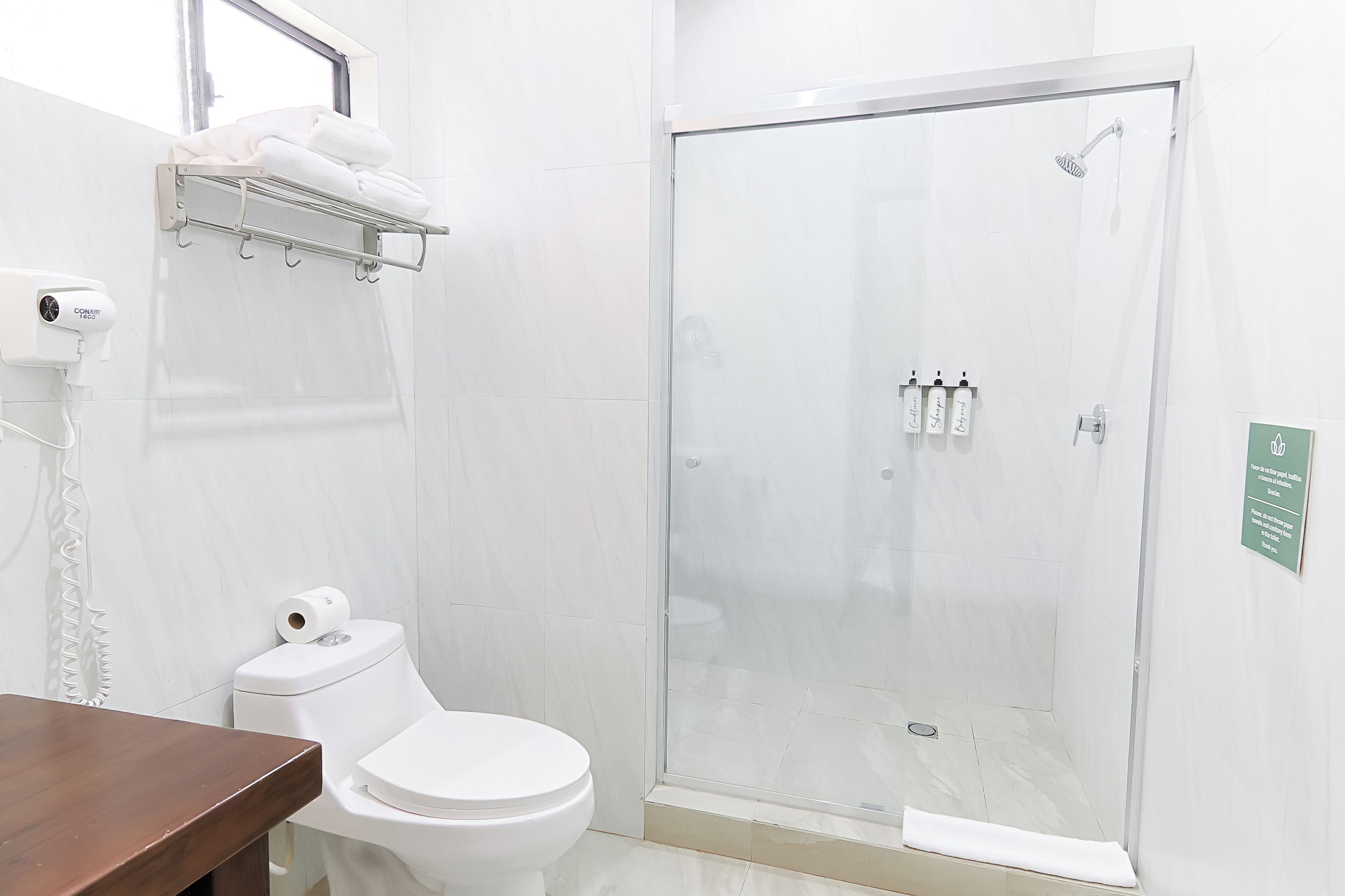 Une salle de bain comprenant des toilettes, une douche avec une porte en verre et un porte-serviettes.