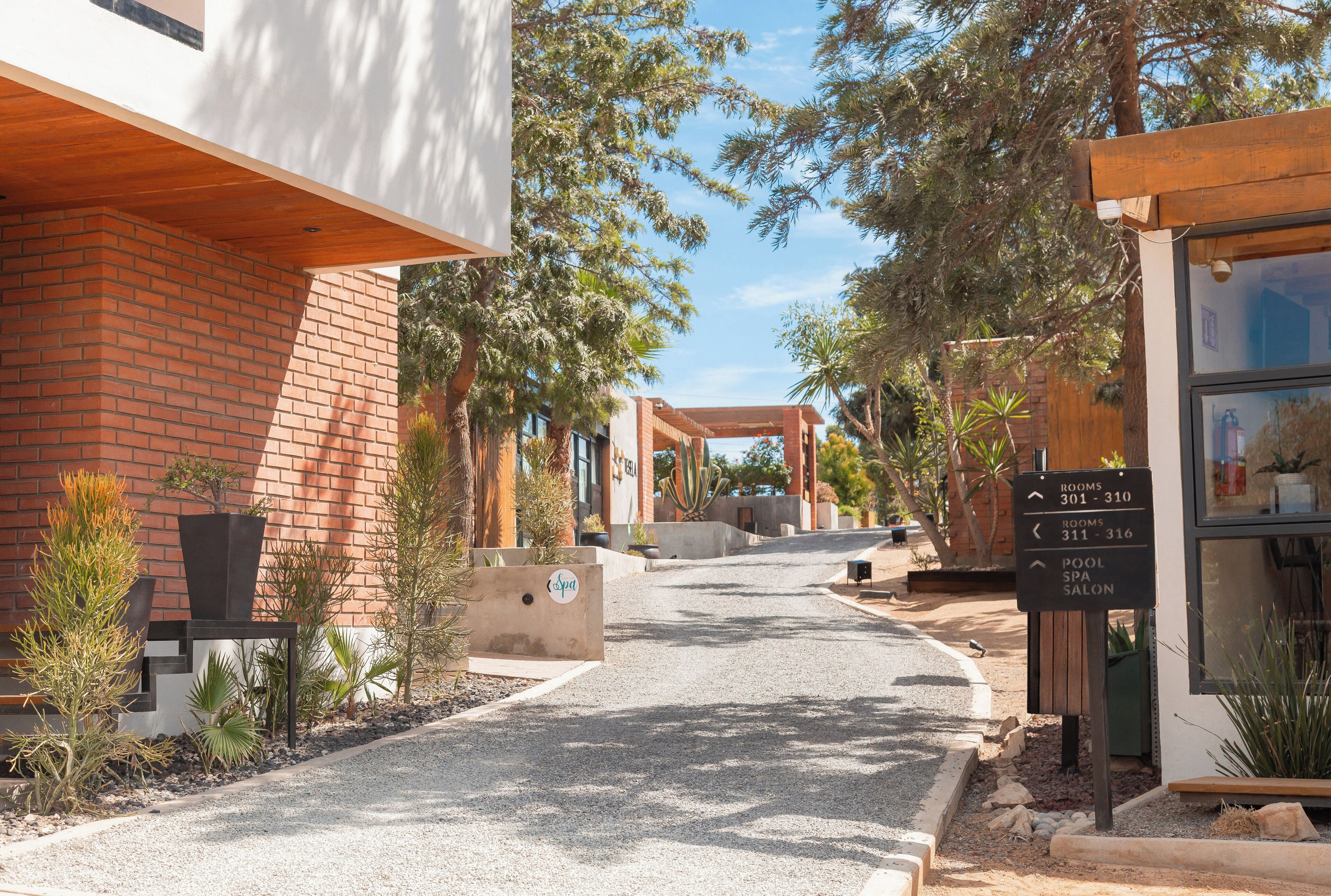 A pathway leading to a building with a spa and pool area, surrounded by landscaped gardens and trees.
