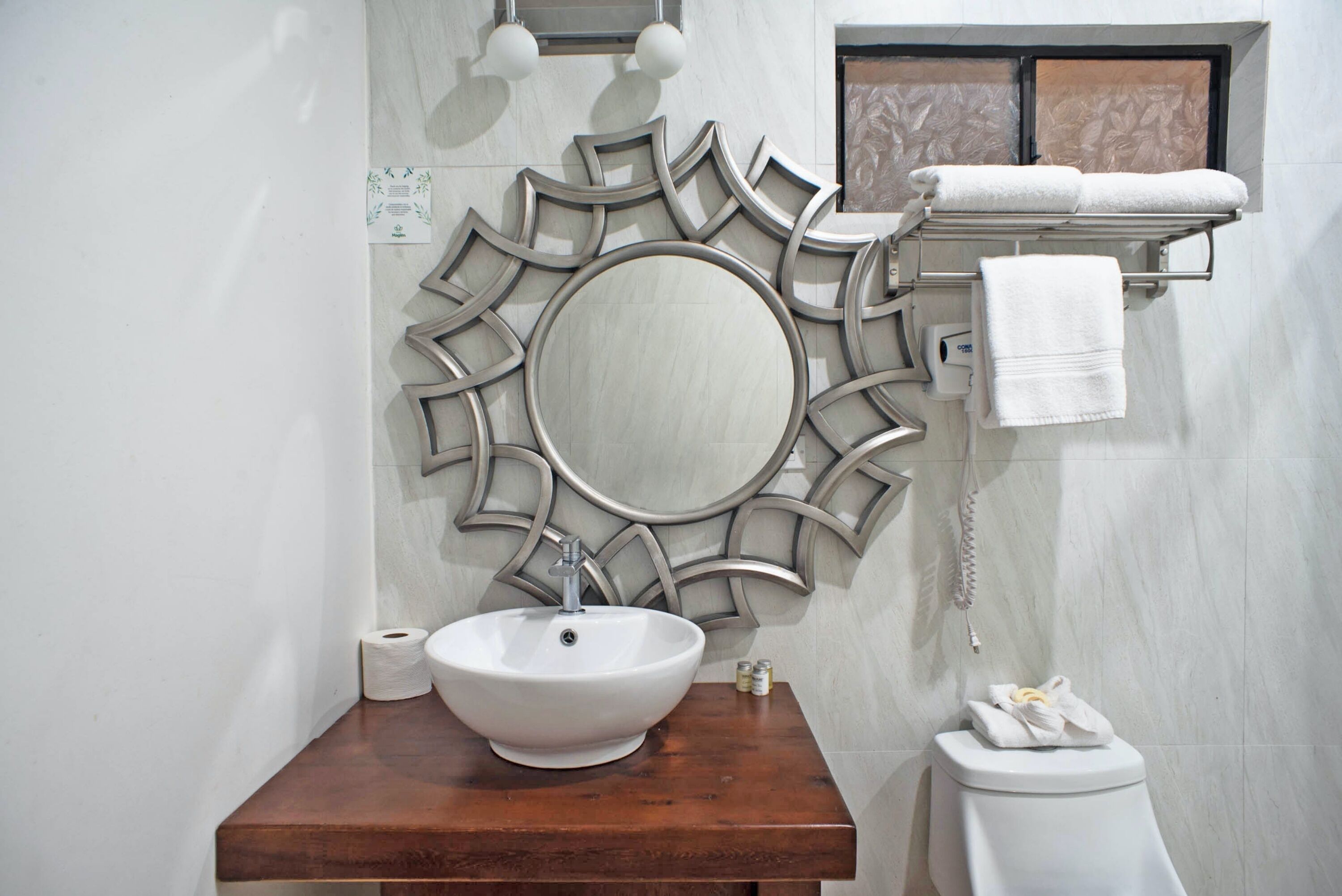 A bathroom with a wooden vanity, a large mirror, a toilet, and a towel rack.