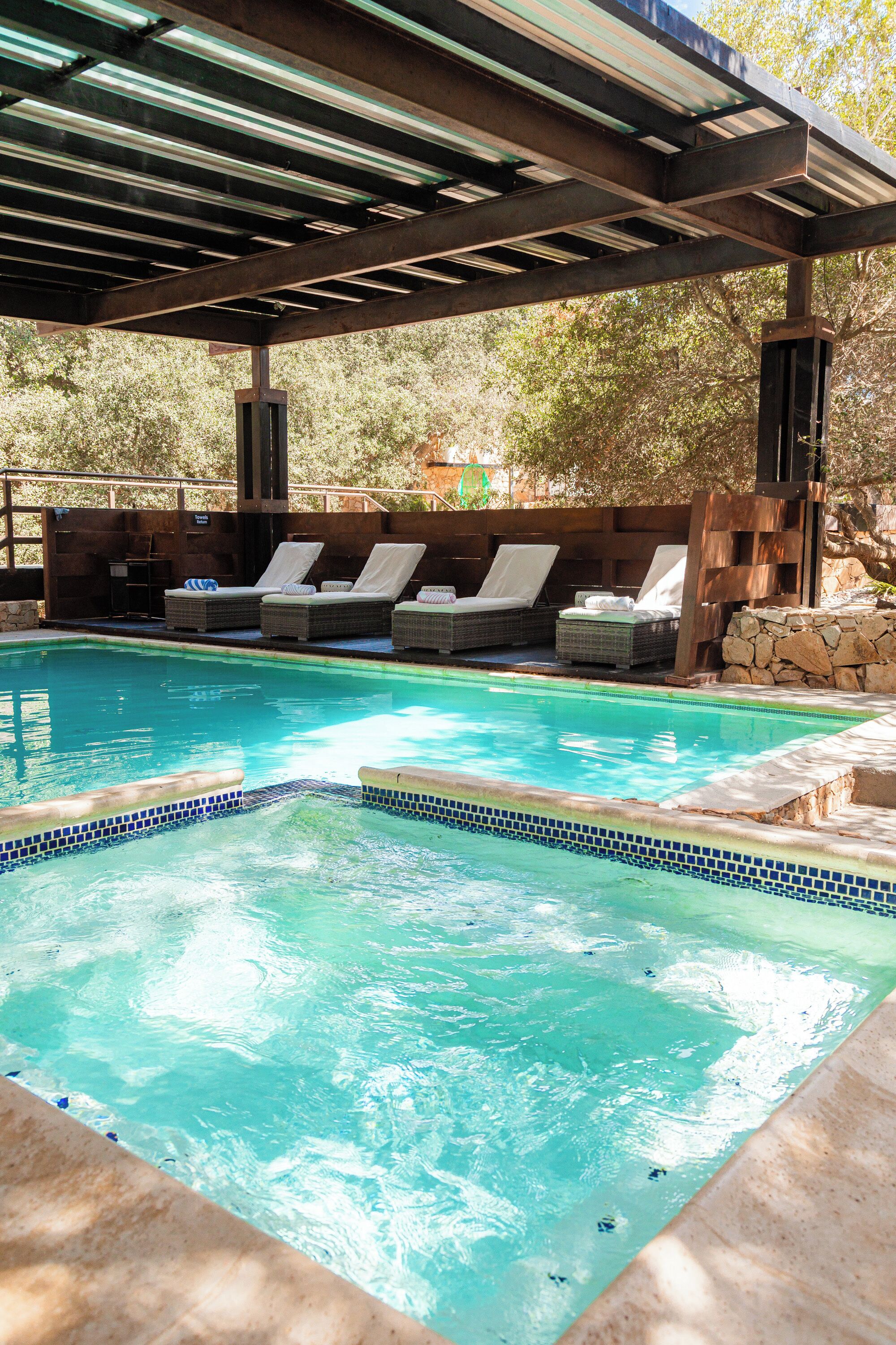 Un área de piscina con sillas de descanso y una pérgola.