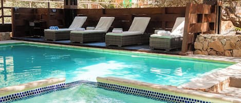 Un área de piscina con sillas de descanso y una pérgola.