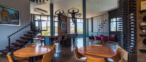 Interior moderno com uma mesa de jantar de madeira, cadeiras, escada e espaço para vinhos.
