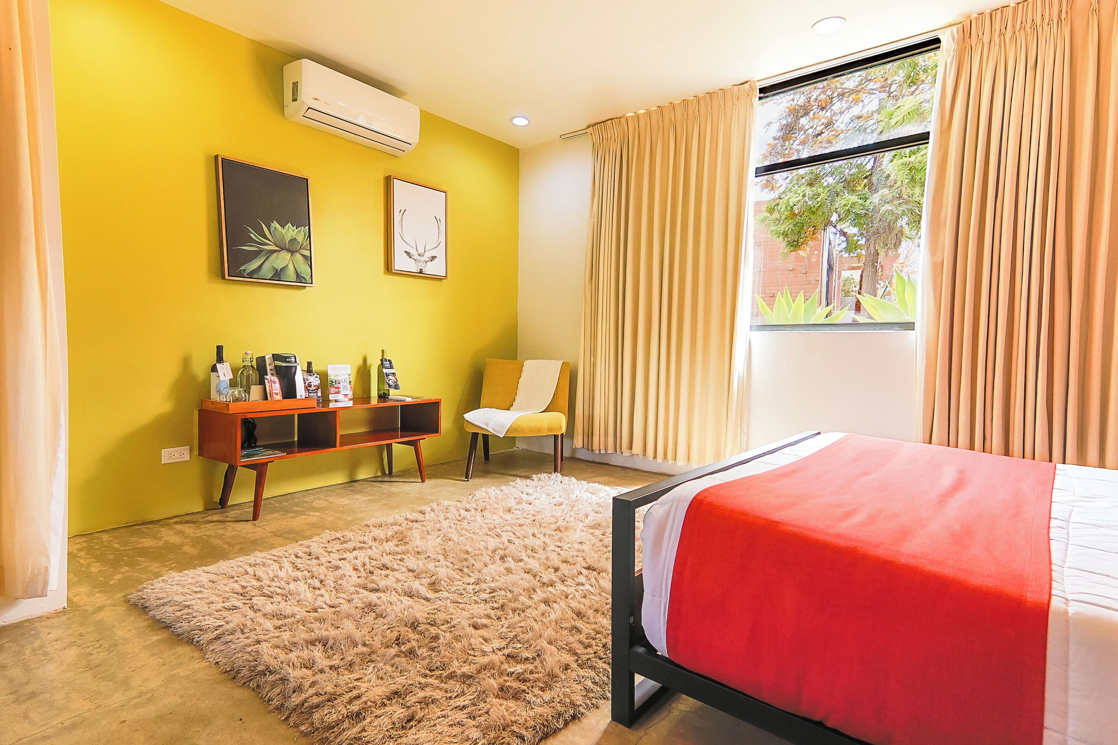 Un dormitorio con cama, sofá, una mesita y una ventana con cortinas.