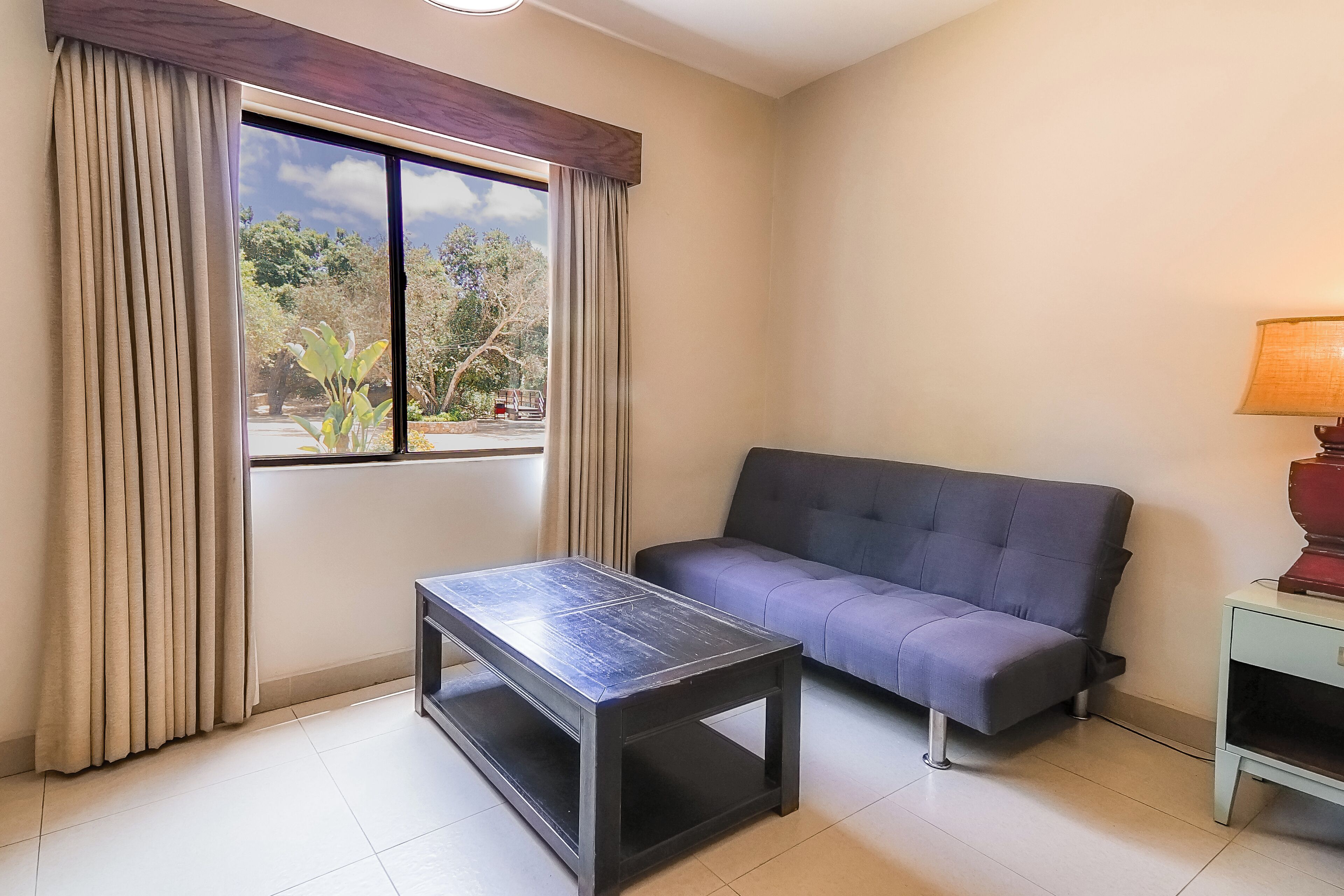 Una habitación con sofá, mesa y lámpara.