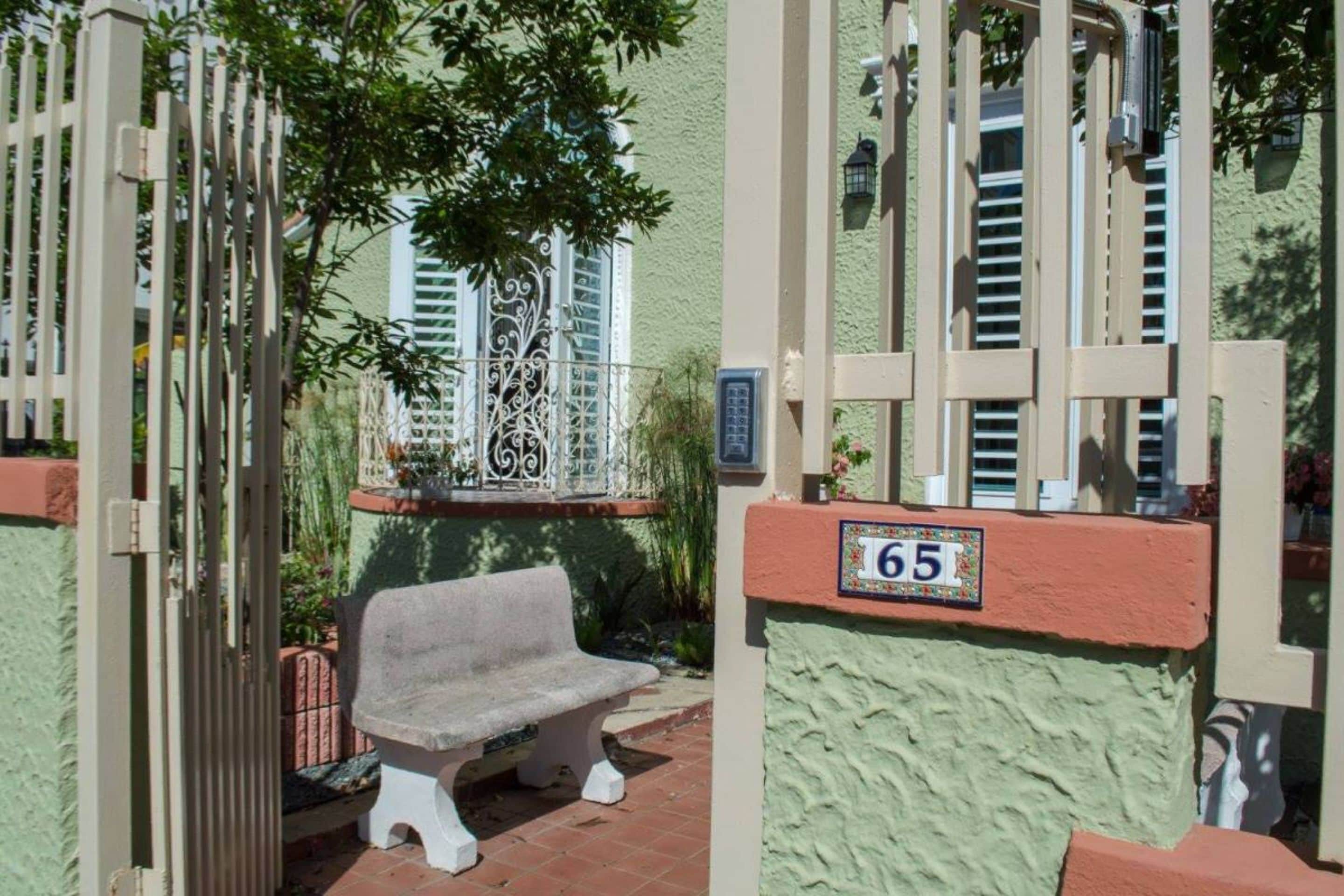 A gated entrance with a number plaque '65' and a bench outside.