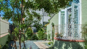 A courtyard with a paved pathway, a small garden area with plants, and a decorative metal fence. - Casa Isabel Bed & Breakfast (San Juan)