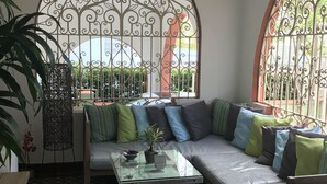 A cozy seating area with a checkered floor, a glass coffee table, and a sofa with colorful cushions. - Casa Isabel Bed & Breakfast (San Juan)