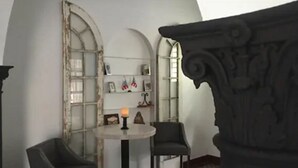 A room with a round table, two chairs, a candle, and a bookshelf with various items. - Casa Isabel Bed & Breakfast (San Juan)