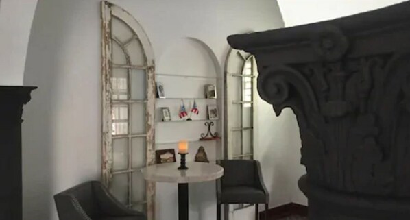 Una habitación con una mesa redonda, dos sillas, una vela y una estantería con varios objetos.