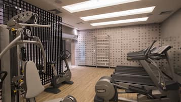 Un gimnasio moderno con diversos equipos de ejercicio, como cintas de correr y máquinas de pesas, y una pared con diseño.