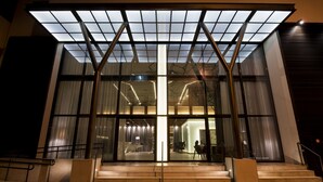 Un edificio moderno con fachada de vidrio, ventanas amplias y una entrada destacada con escalones.