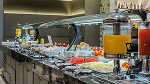 Un bufé con diferentes opciones de comida y un dispensador de zumo.