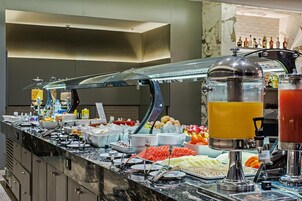 Buffet com diversos alimentos e um dispensador de sucos.