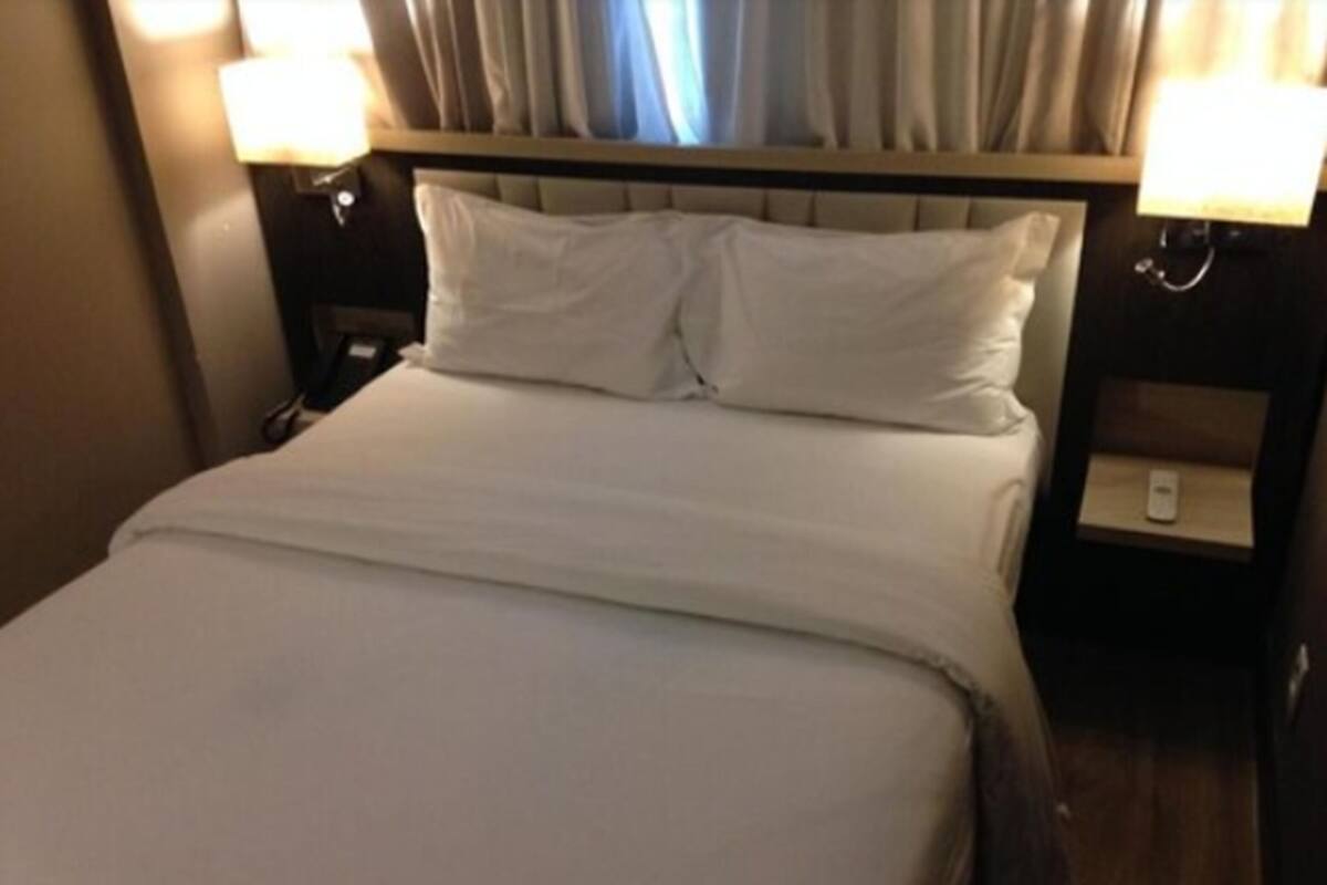 Quarto de hotel com uma cama, duas mesas de cabeceira e luminárias.