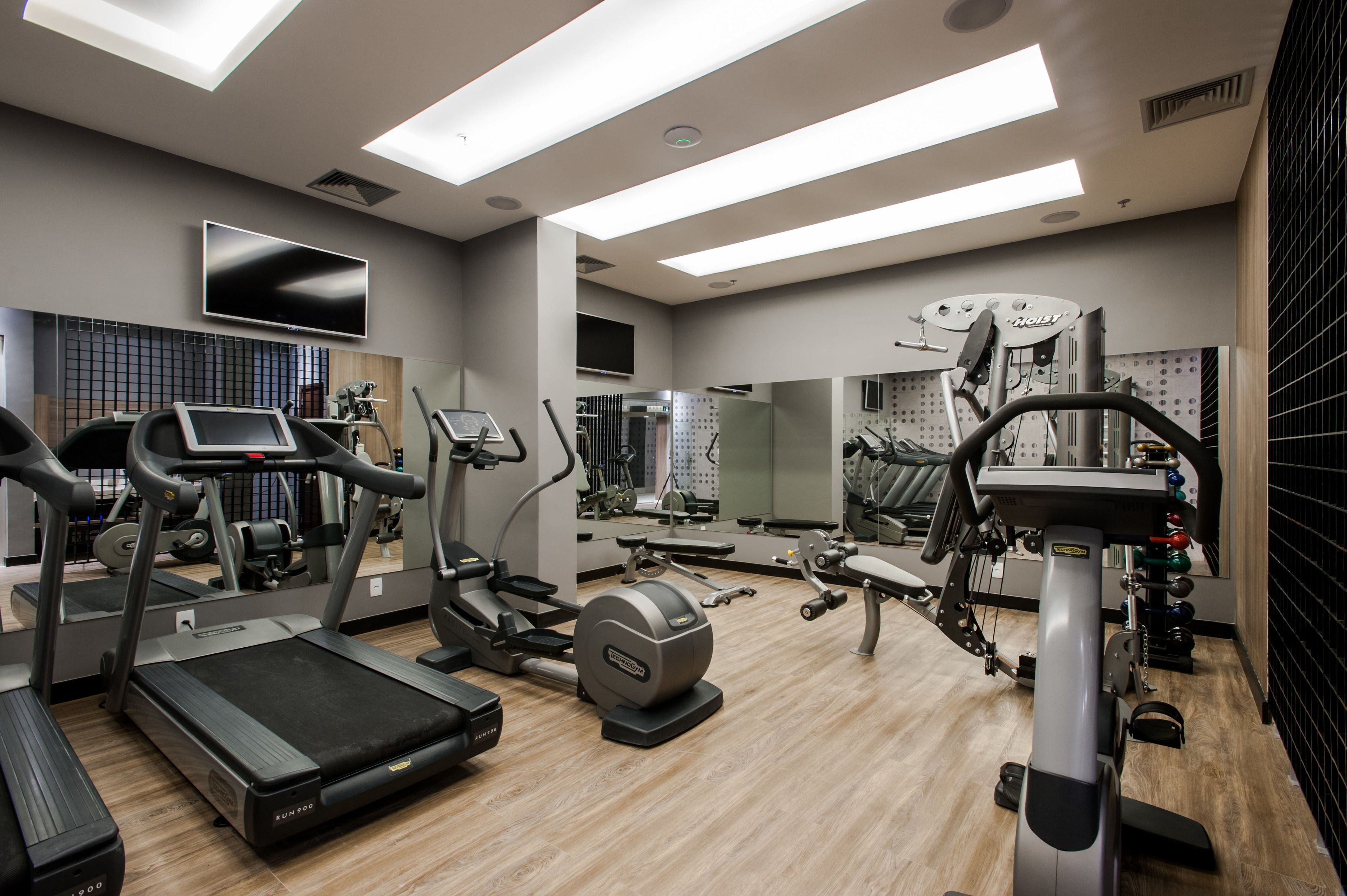 A modern gym with treadmills, elliptical machines, and weight equipment.