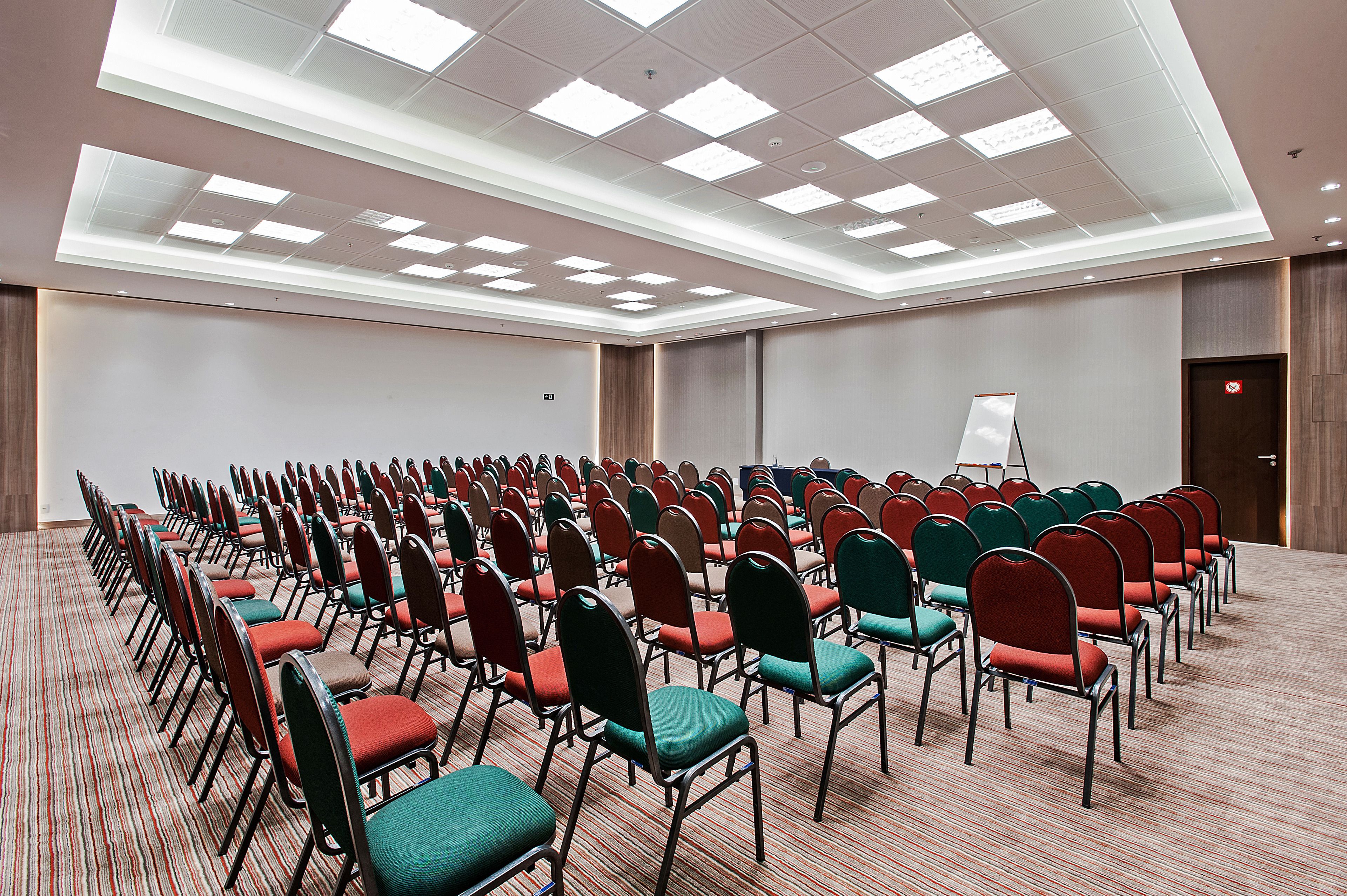 A conference room with rows of chairs, a whiteboard, and a carpeted floor.