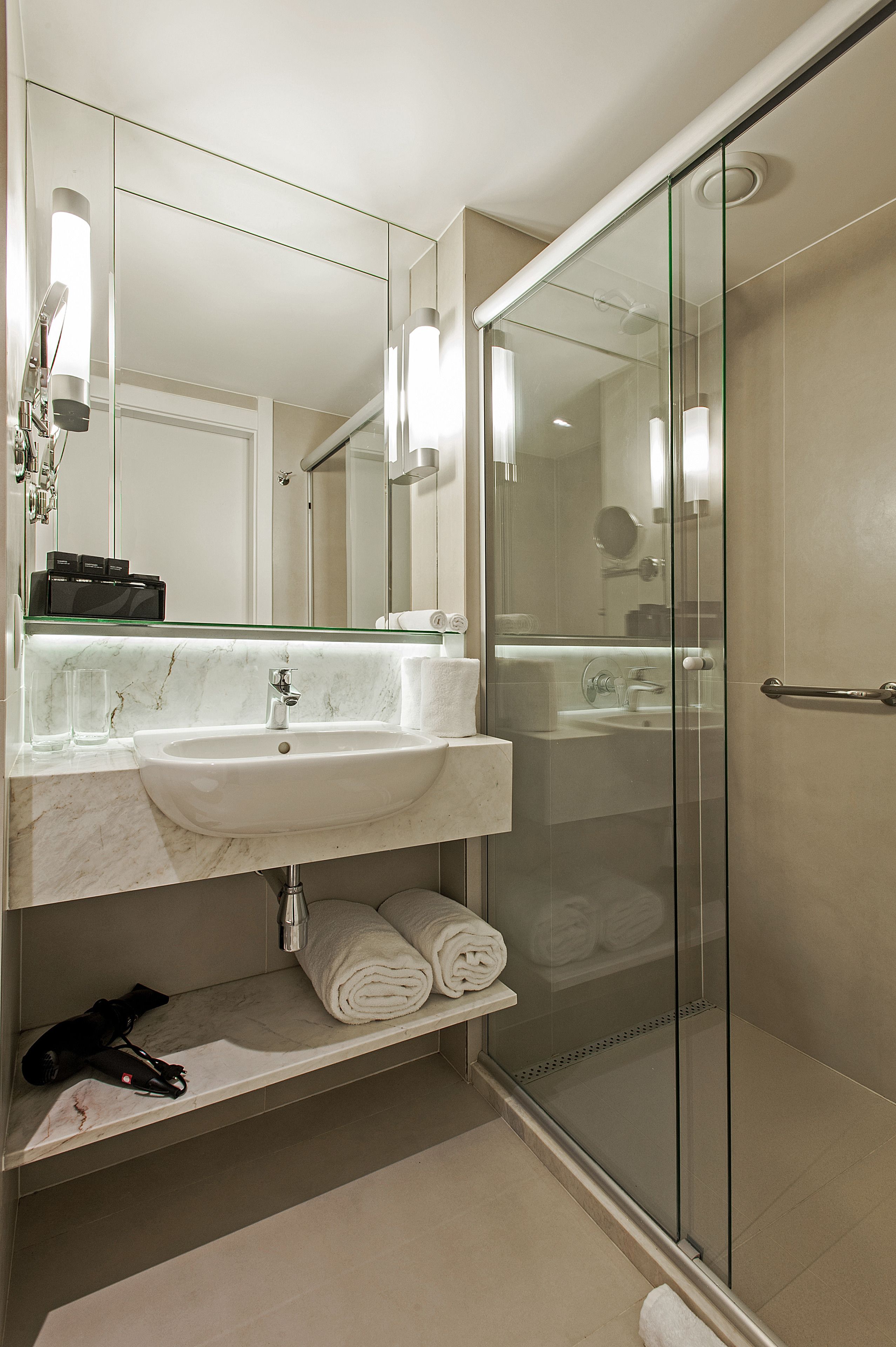 A modern bathroom with a glass-enclosed shower, a marble sink, and a large mirror.