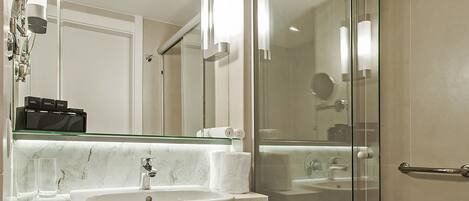 A modern bathroom with a glass-enclosed shower, a marble sink, and a large mirror.