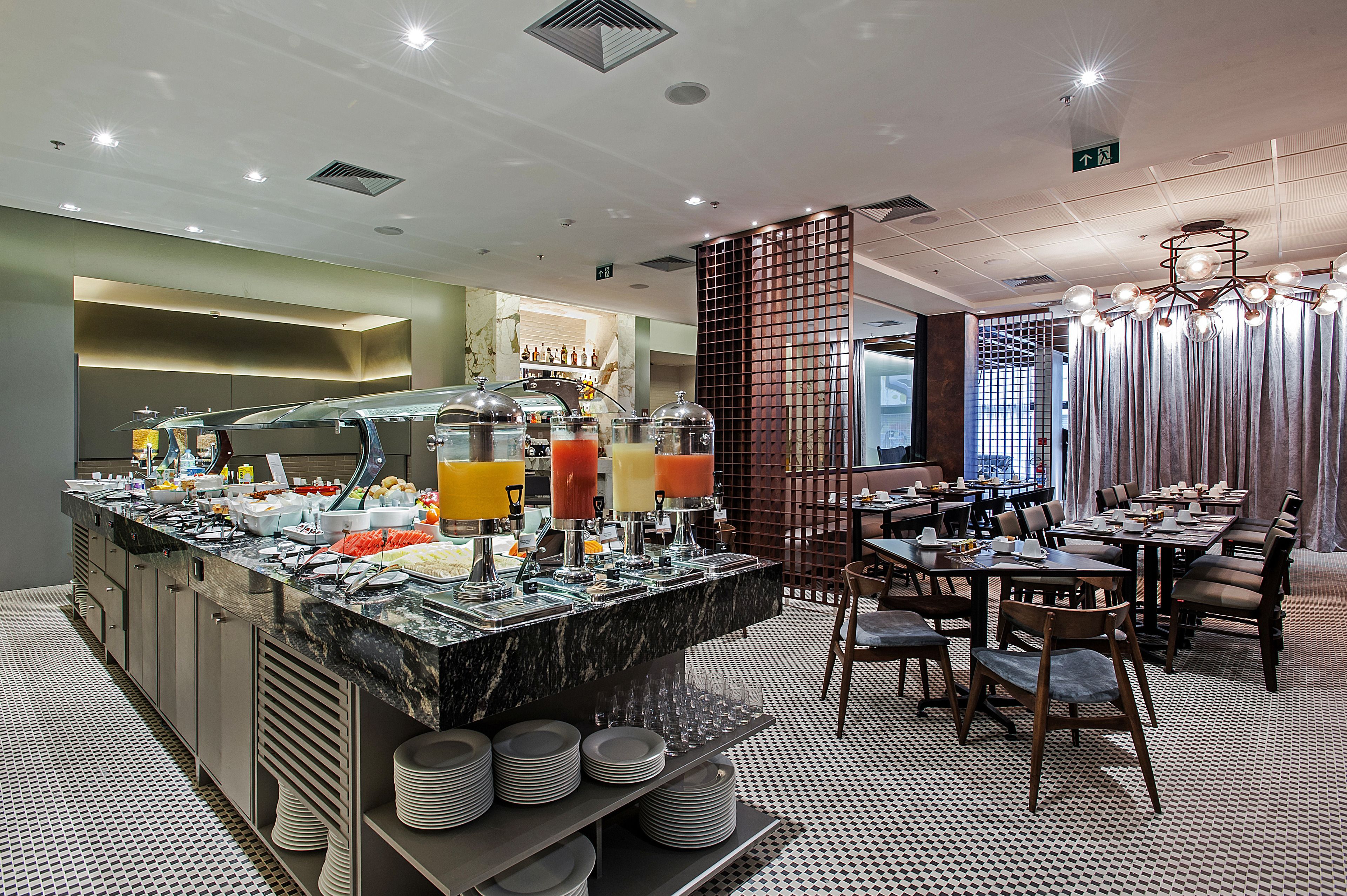 Uma área de buffet com balcão de mármore, diversos dispensadores de bebidas e uma variedade de alimentos.