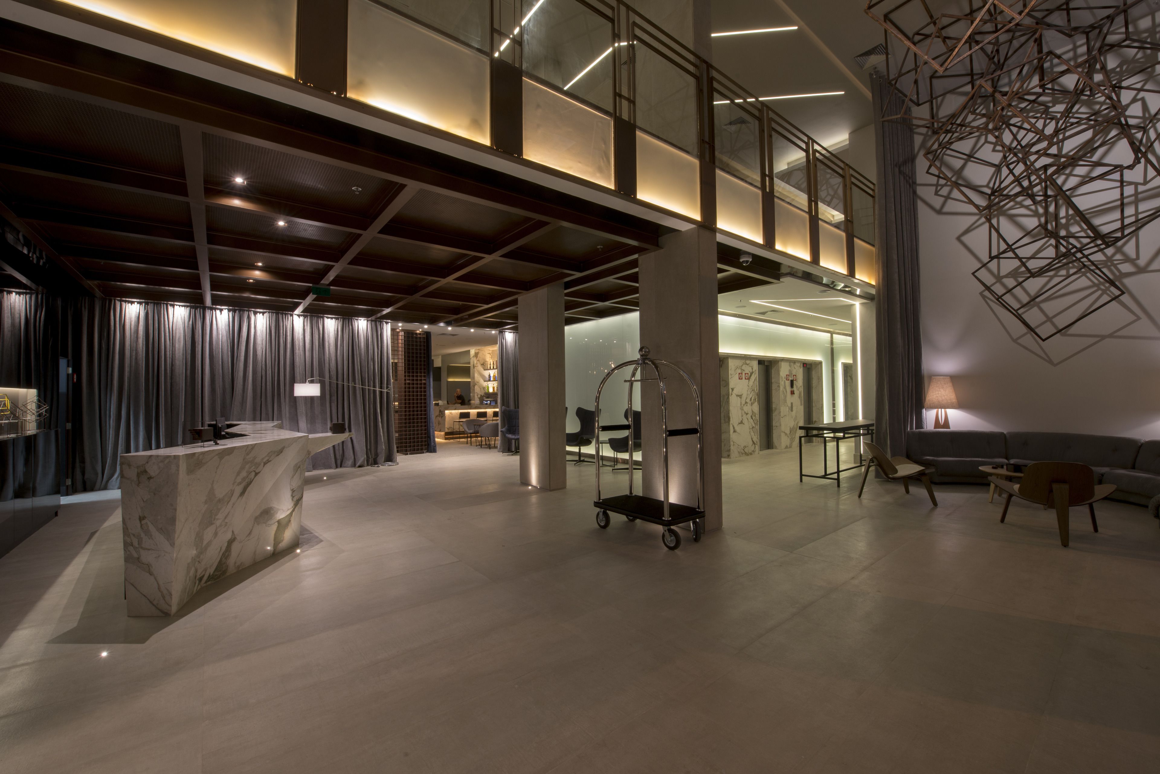 A spacious lobby with a marble reception desk, a cart, and seating area with a modern chandelier.