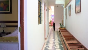 Un pasillo estrecho con piso estampado, una cama a la izquierda y una escalera a la derecha.