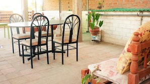 Un espacio al aire libre con mesa y sillas, un sofá y plantas en macetas.